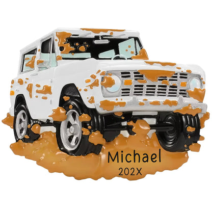 Personalized off-road truck Christmas ornament, a white lifted 4x4 splattered with orange mud, engraved with a custom name and year in the mud at the base.