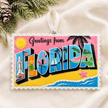 Personalized Florida postcard christmas ornament laid on a soft white knit blanket