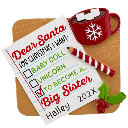 Dear Santa ornament with checklist reading “To Become a Big Sister,” personalized with name and year, featuring cocoa mug and candy cane pencil