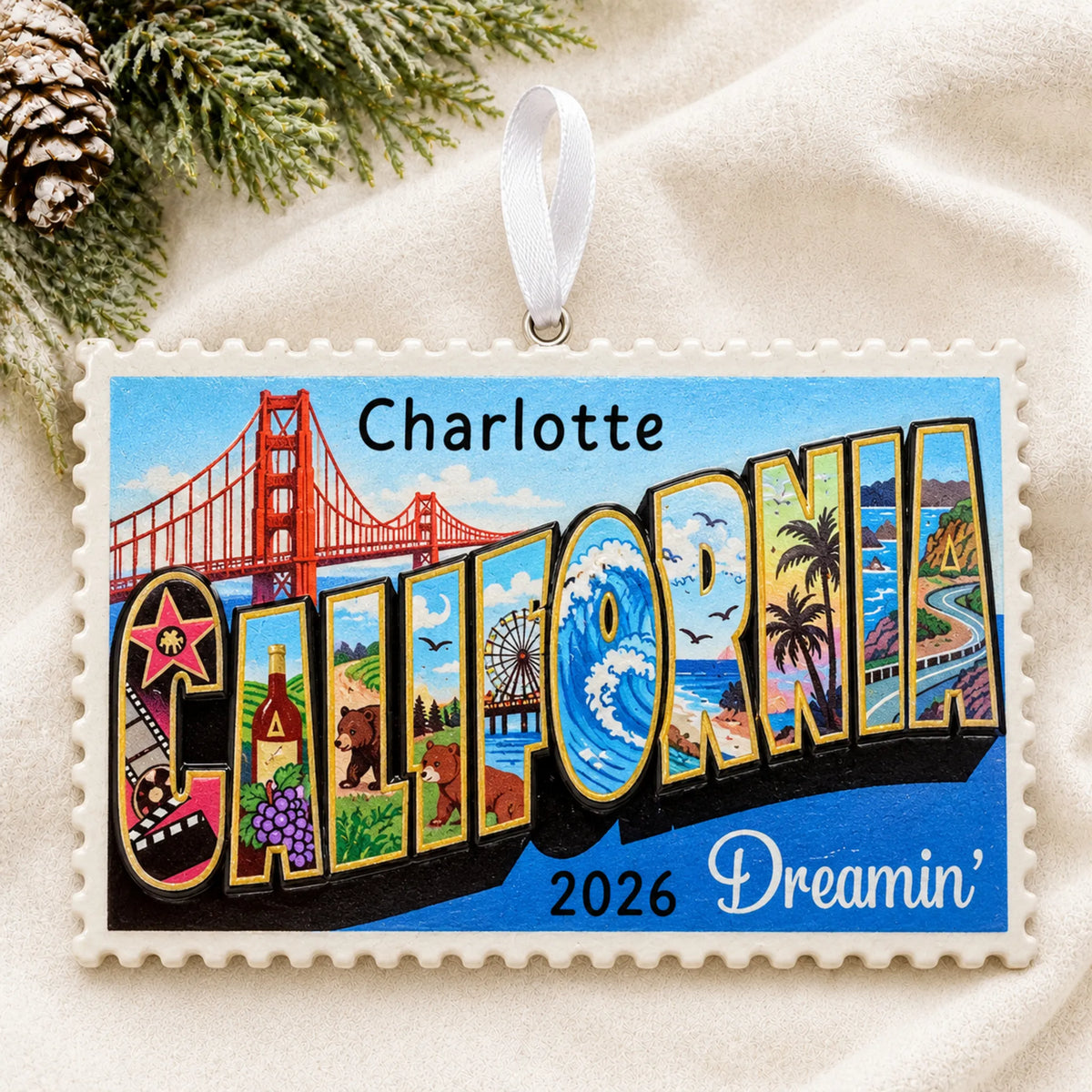 Personalized California postcard christmas ornament laid on a soft white knit blanket