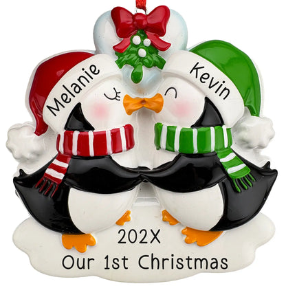 Personalized couple Christmas ornament with two penguins behind a red heart, sample message Our 1st Christmas, laser engraved with both names and the year