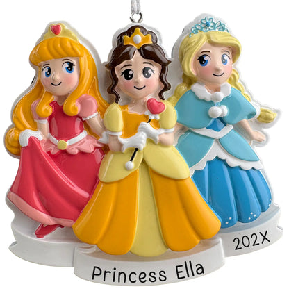 Personalized princess Christmas ornament with three storybook princesses in pink, yellow, and blue gowns, name engraved on the front banner and year beside it