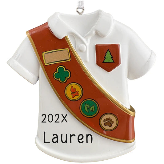 Personalized Girl Scout ornament, white uniform shirt with brown badge sash and pine tree pocket patch, name and year laser engraved on the shirt front