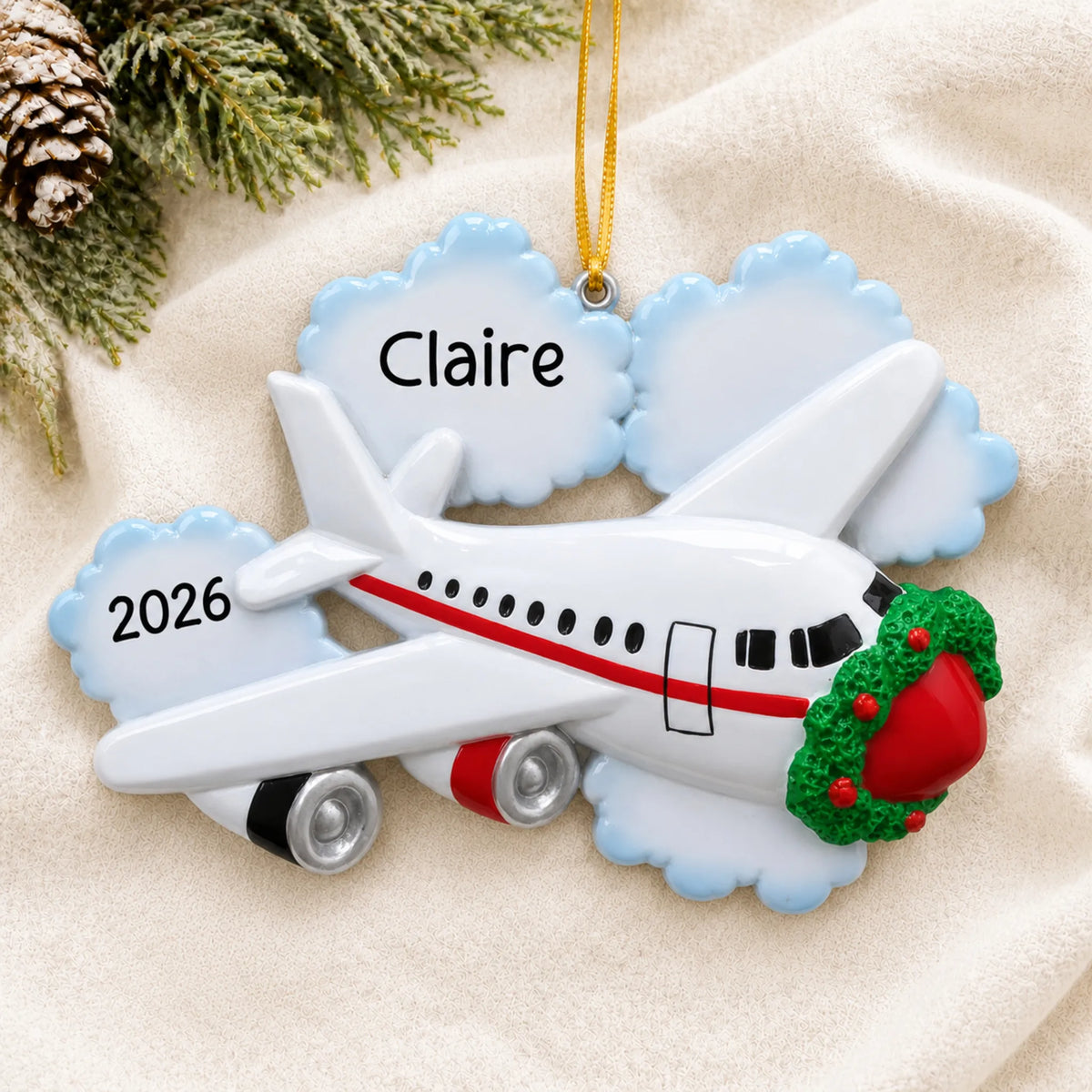 Personalized jet airplane travel christmas ornament laid on a soft white knit blanket