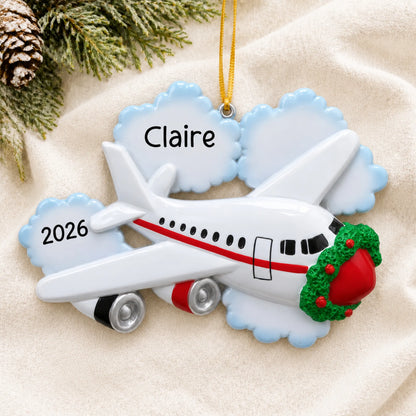 Personalized jet airplane travel christmas ornament laid on a soft white knit blanket