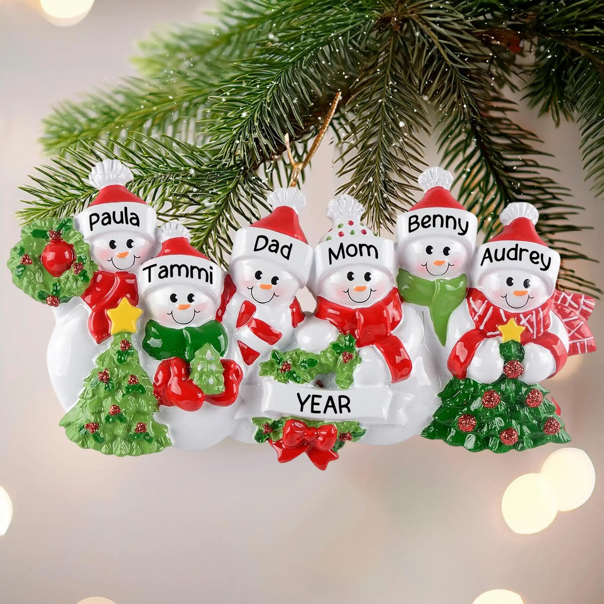 Personalized snowman family ornament with names on a Christmas tree.