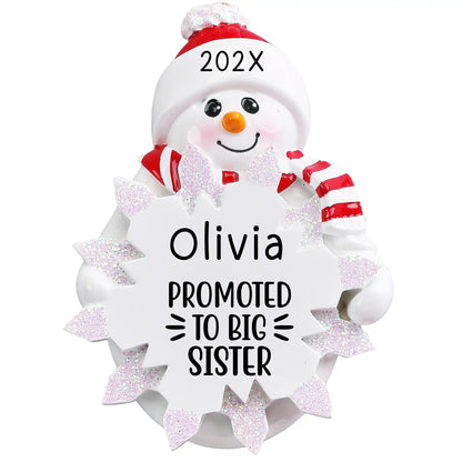 Personalized snowman ornament with “Promoted to Big Sister” engraving, red hat and scarf, and glitter snowflake personalized with name and year.