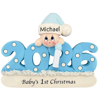 A blue 2026 Baby’s 1st Christmas ornament featuring a smiling baby in a glittery hat holding a bottle.