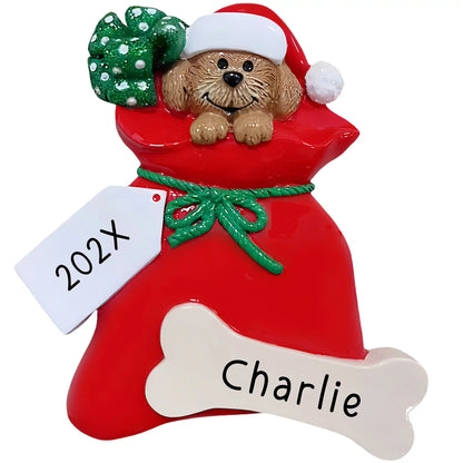 Personalized puppy ornament with brown dog in Santa hat peeking out of red gift bag, name engraved on gift tag and year on bone