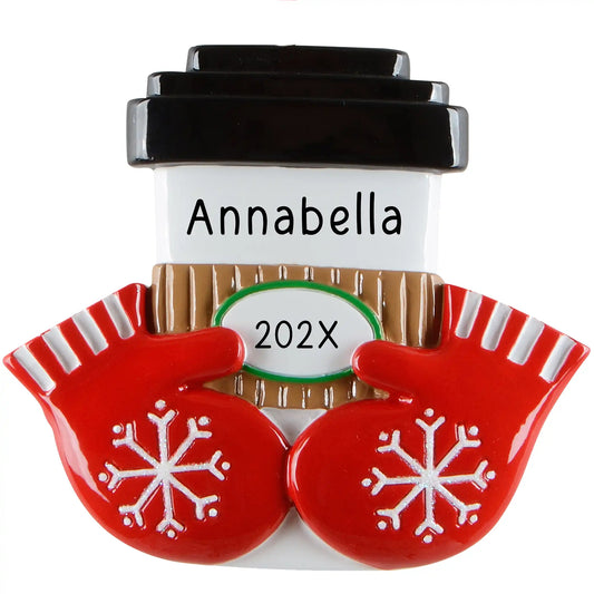 A personalized Christmas ornament of a white coffee cup with a black lid and brown sleeve held by red snowflake mittens, featuring space for custom names.