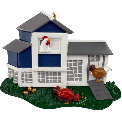 A personalized Christmas ornament of a blue and white chicken coop with chickens in the grass, featuring space for custom engraved names.