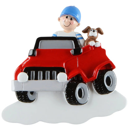 A personalized Christmas ornament of a boy and a dog in a red ride on electric truck, featuring a white base for custom engraved names.