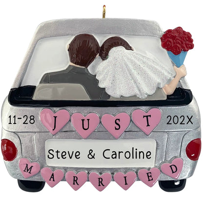 A personalized Christmas ornament of a silver getaway car with pink hearts and a bride and groom inside, featuring space for a custom name on the license plate.