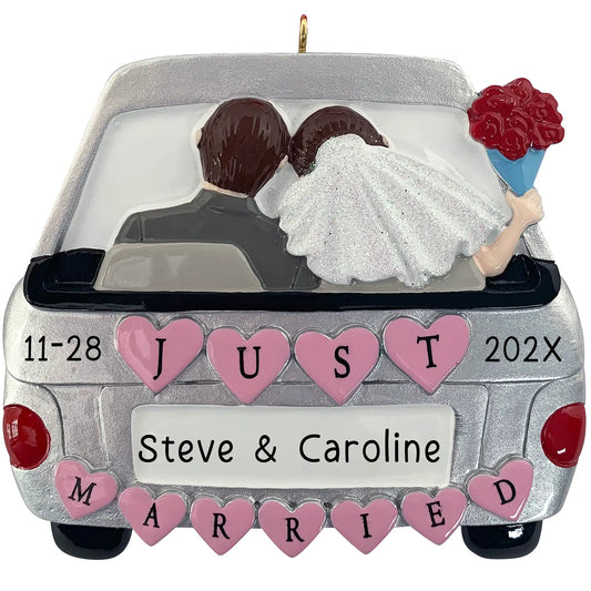 A personalized Christmas ornament of a silver getaway car with pink hearts and a bride and groom inside, featuring space for a custom name on the license plate.