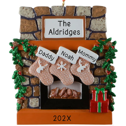 Personalized family of 3 Christmas ornament, a rustic stone fireplace with three named stockings, garland, and a lit hearth, engraved The Aldridges with the year