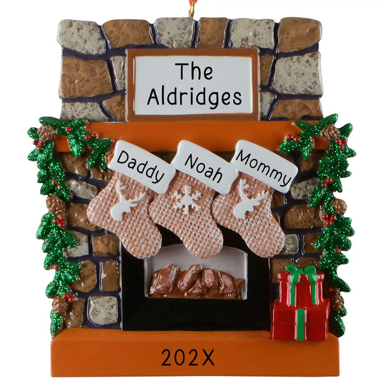 Personalized family of 3 Christmas ornament, a rustic stone fireplace with three named stockings, garland, and a lit hearth, engraved The Aldridges with the year