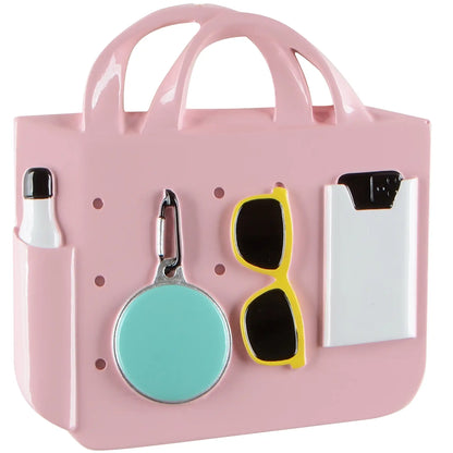 A personalized Christmas ornament of a pink rubber beach tote bag with sunglasses and a water bottle, featuring space for a custom-engraved name.