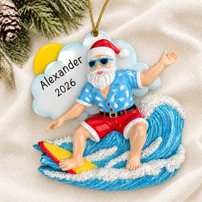 Personalized big wave surfing Santa christmas ornament laid on a soft white knit blanket