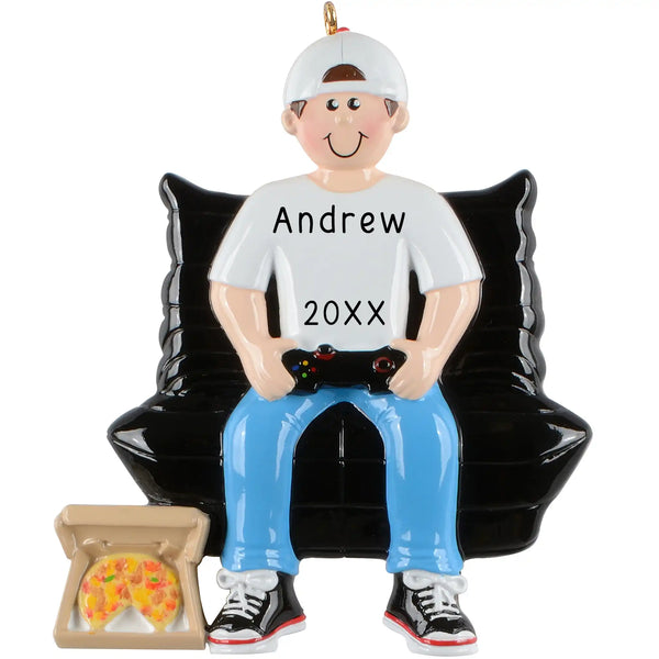 A personalized ornament depicting a cartoonish male figure with a gaming controller and a pizza box, seated on a couch. The ornament is customizable with names and years.