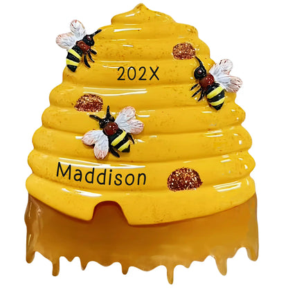 Personalized beehive Christmas ornament, a honey-dripping skep hive with three bees, engraved with the name Maddison and the year