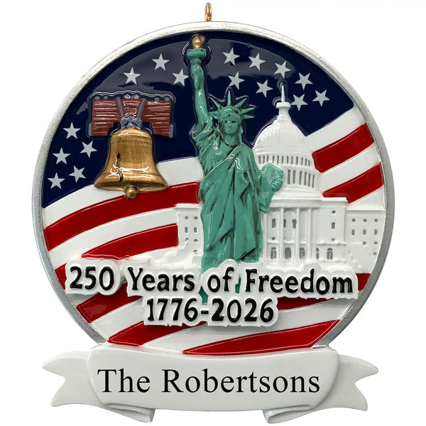 Personalized 250th-anniversary USA ornament featuring the Statue of Liberty, Liberty Bell, and U.S. Capitol on a flag background with a blank white scroll for engraving.