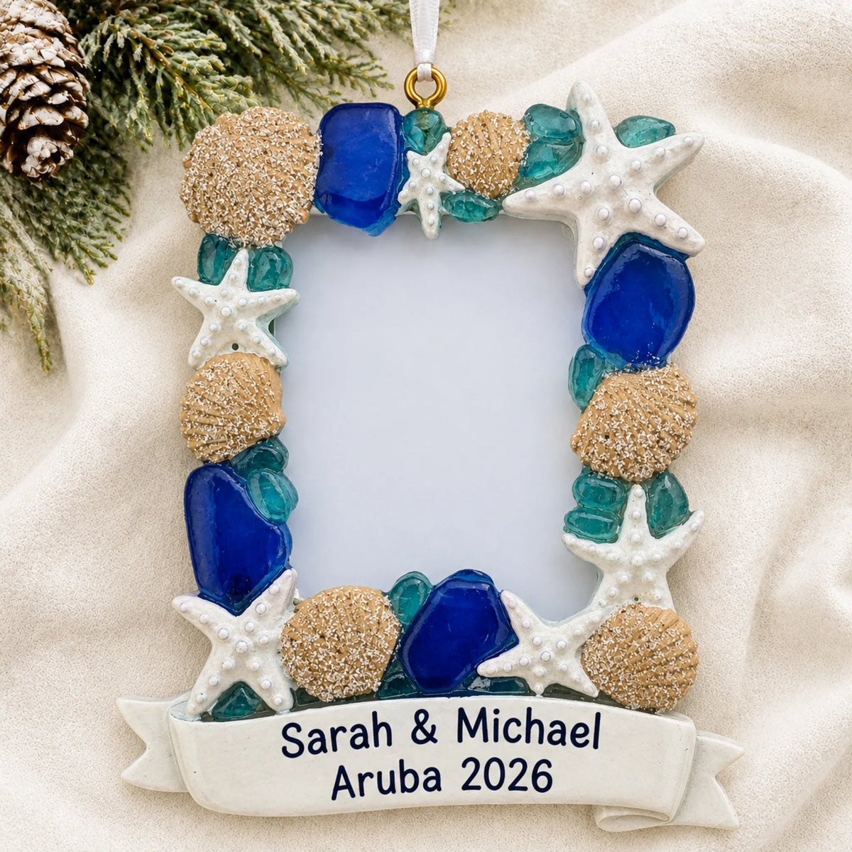Personalized beach seashells photo frame christmas ornament laid on a soft white knit blanket