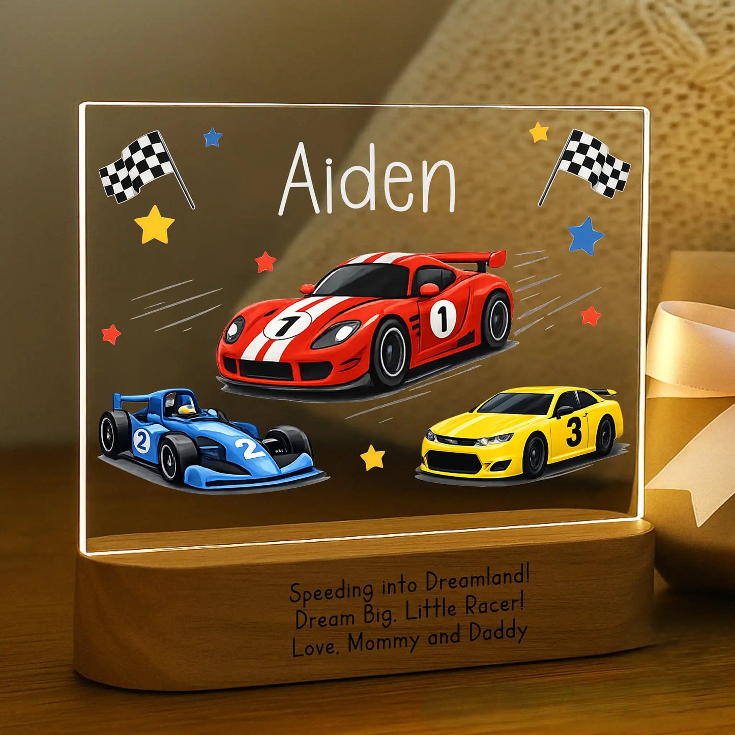 Personalized race car night light glowing with custom name Aiden laser engraved on acrylic and Speeding Into Dreamland message laser engraved on acacia wood base.