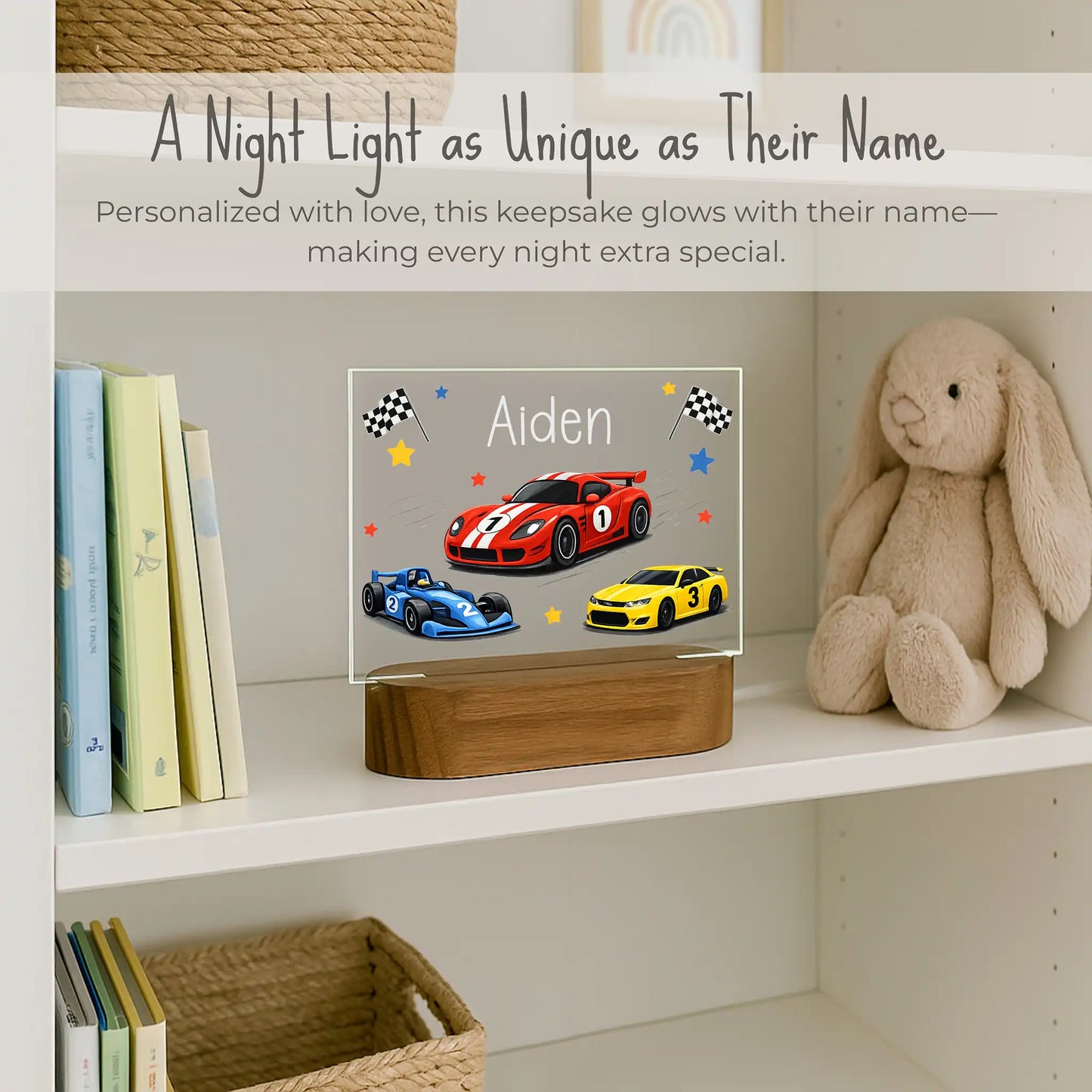 Custom name race car night light on boys bookshelf, acrylic plate with red blue and yellow race cars and checkered flags, name Aiden laser engraved, warm LED glow on acacia wood base