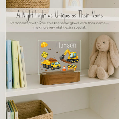 Custom name construction night light sitting on kids bookshelf, acrylic plate with dump truck and excavator design, personalized with child's name, warm LED glow