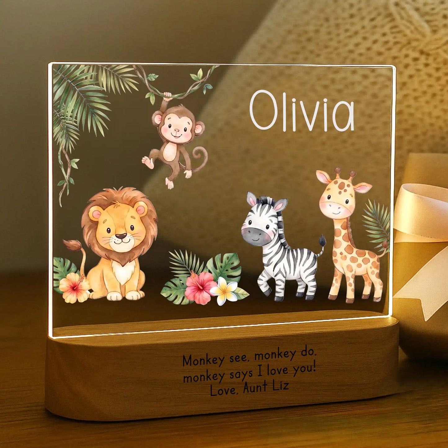 Close-up of child's name Olivia laser engraved in white on personalized safari night light acrylic plate with gift message on wood base