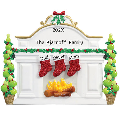 Personalized Christmas ornament featuring a white fireplace mantle with three red glitter stockings and holiday greenery, ready for three custom name engravings.