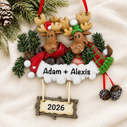 Personalized moose couple christmas ornament laid on a soft white knit blanket