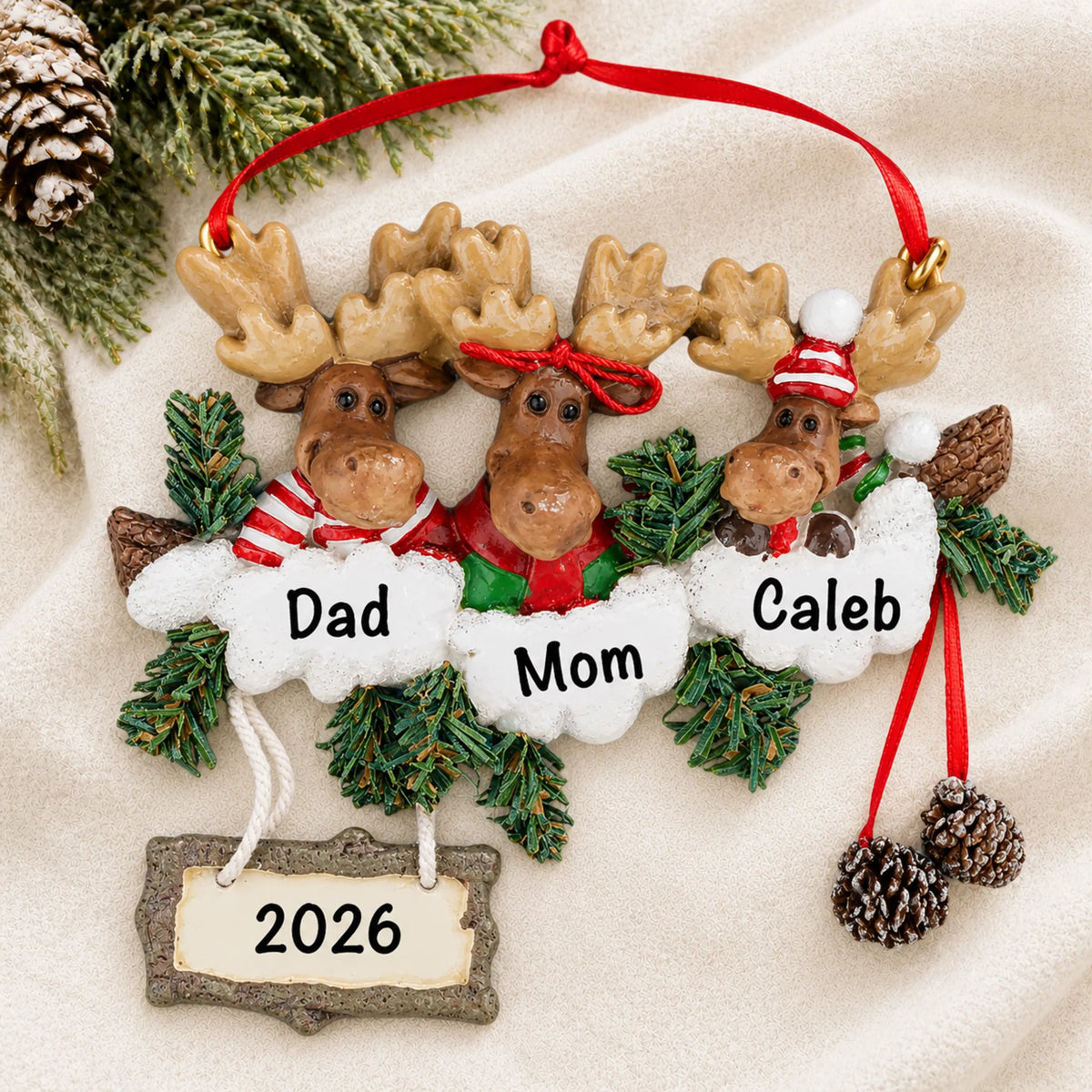 Personalized moose family of 3 christmas ornament laid on a soft white knit blanket
