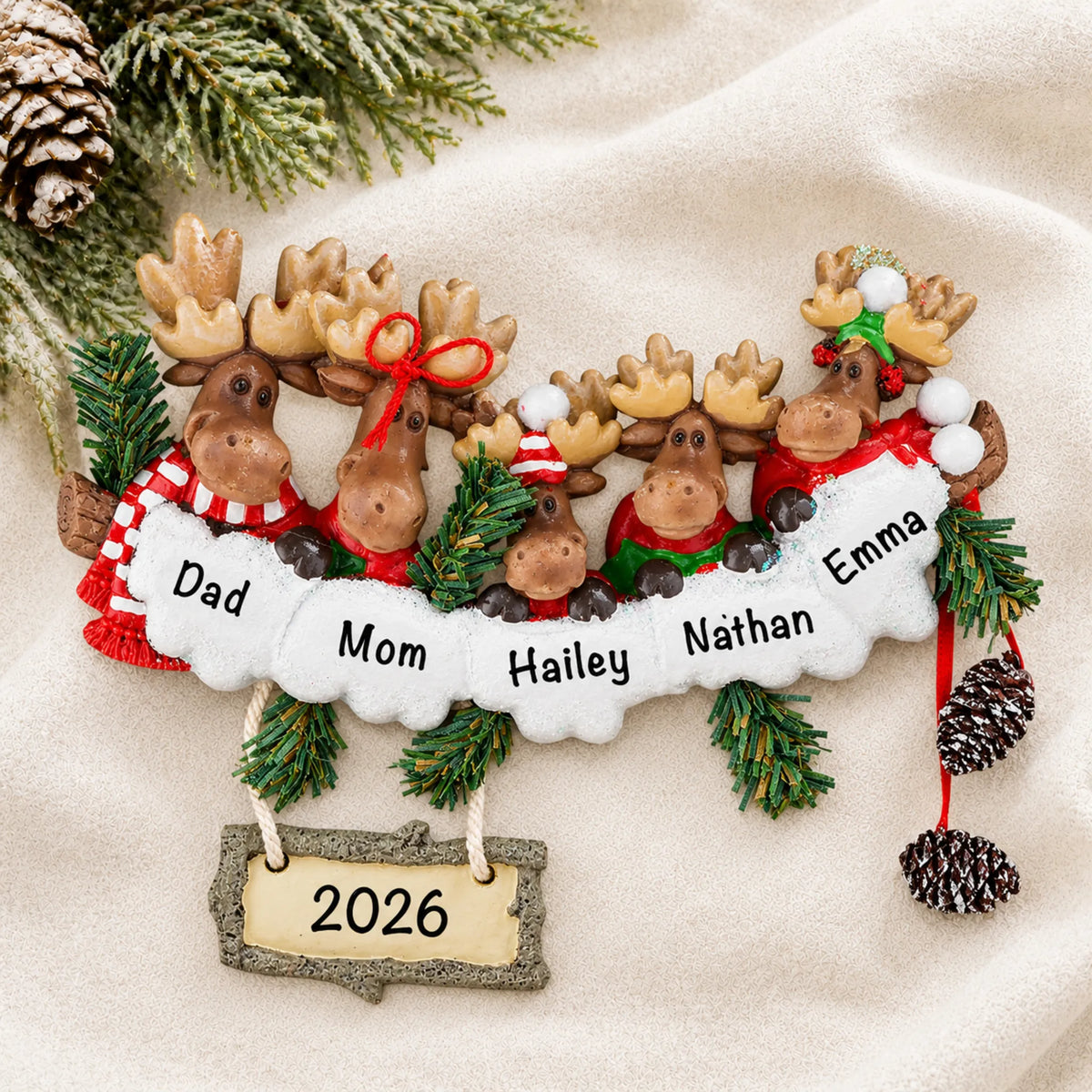 Personalized moose family of 5 christmas ornament laid on a soft white knit blanket