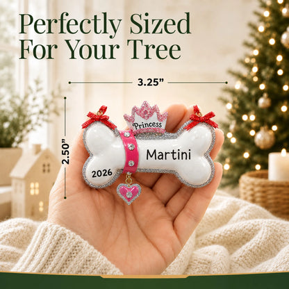 Size guide: the personalized Princess Dog Bone christmas ornament is 3.25 in wide by 2.50 in tall, shown in hand