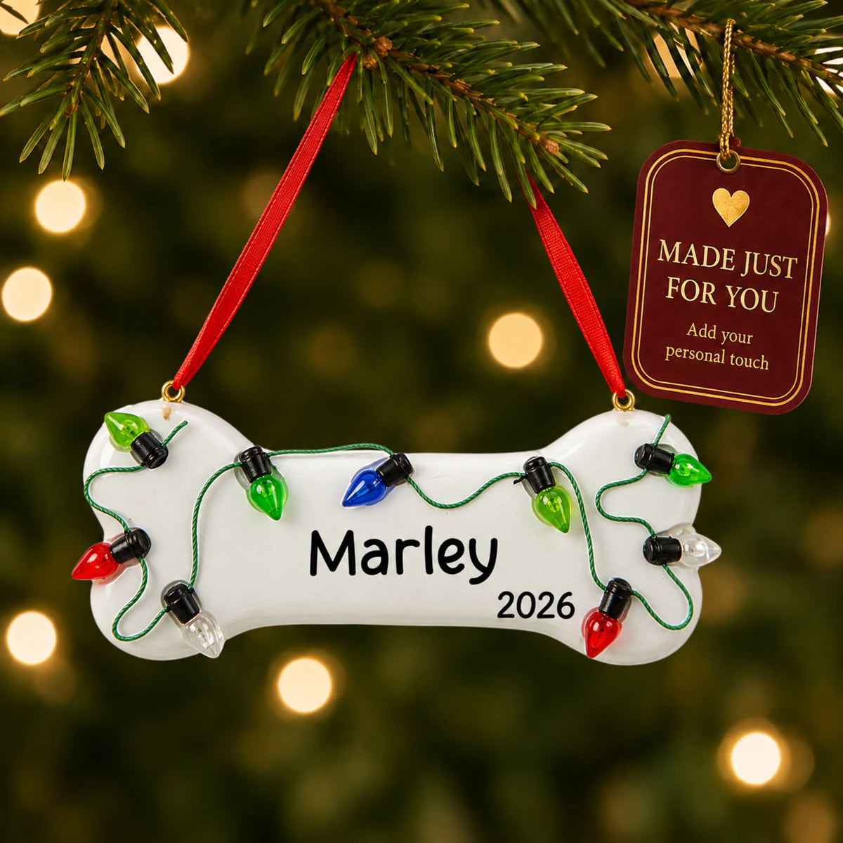 Christmas Lights Dog Bone ornament hanging on a lit Christmas tree with a Made Just For You gift tag