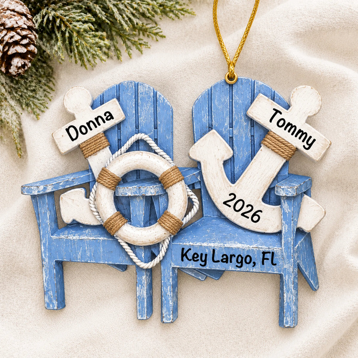 Personalized nautical adirondack chairs christmas ornament laid on a soft white knit blanket