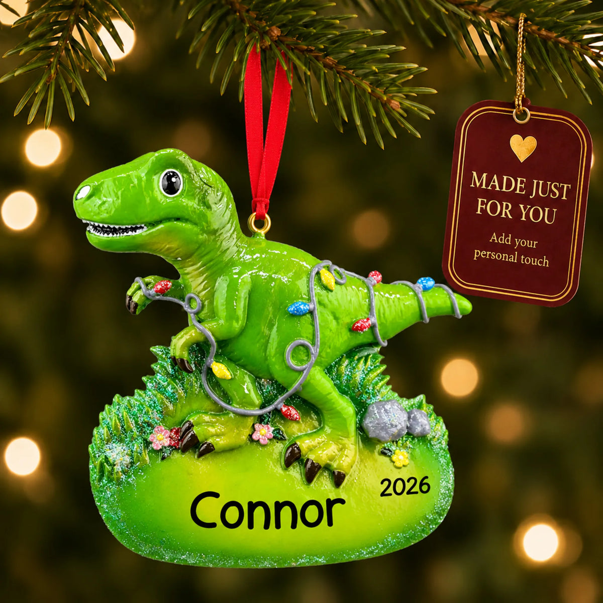 Christmas lights t-rex dinosaur ornament hanging on a lit Christmas tree with a Made Just For You gift tag