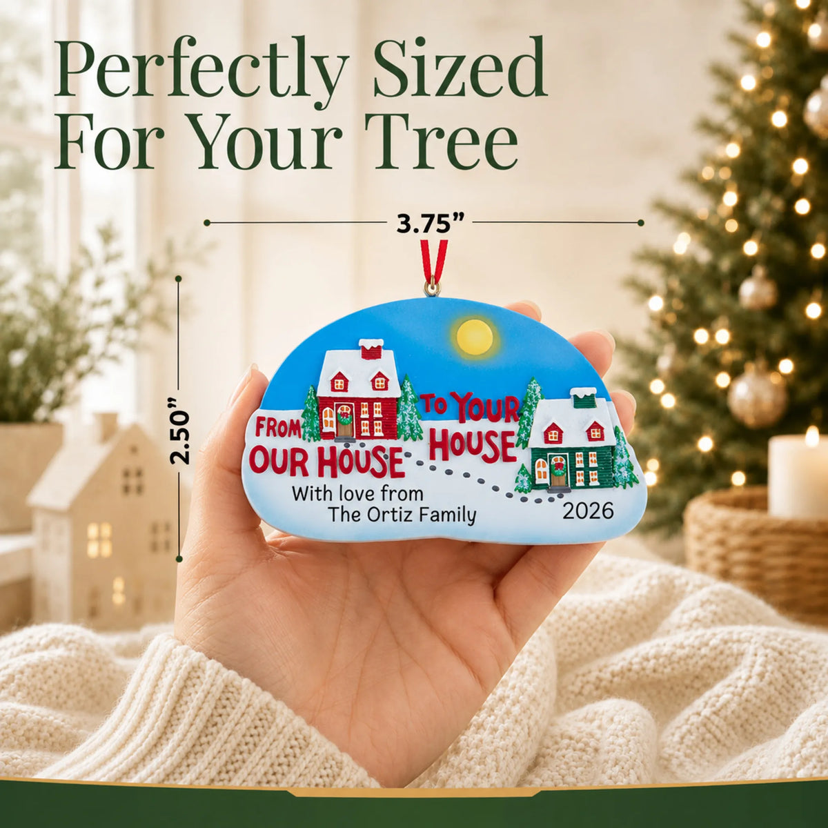 Size guide: the personalized From Our House to Yours christmas ornament is 3.75 in wide by 2.50 in tall, shown in hand