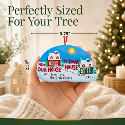 Size guide: the personalized From Our House to Yours christmas ornament is 3.75 in wide by 2.50 in tall, shown in hand