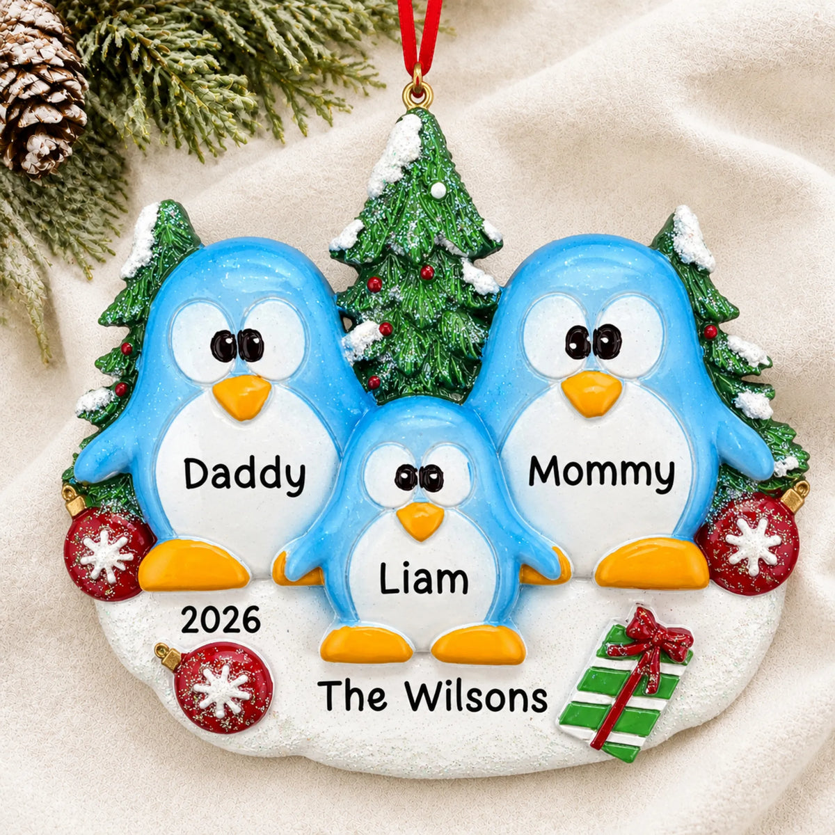 Personalized penguin family of 3 christmas ornament laid on a soft white knit blanket