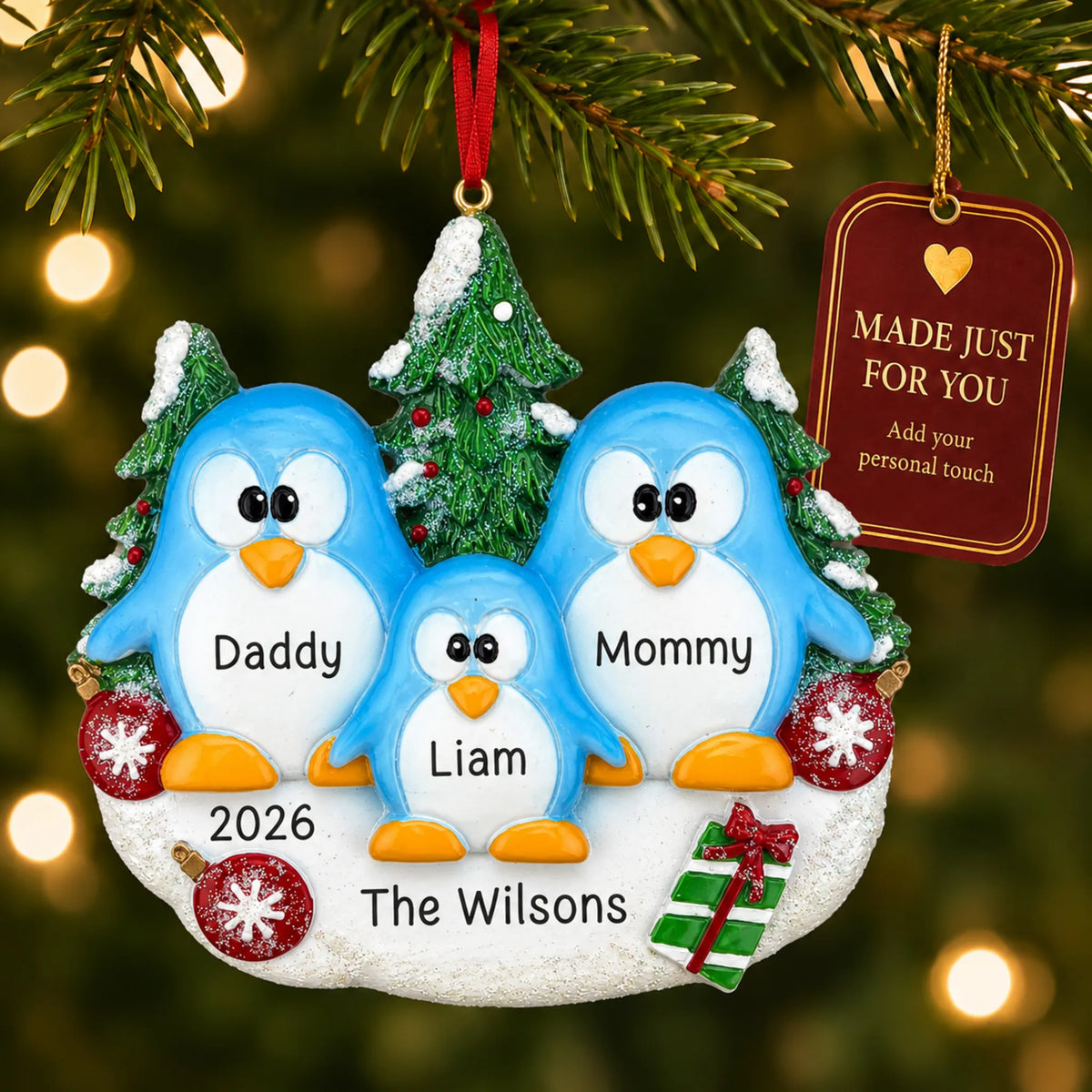 Penguin family of 3 christmas ornament hanging on a lit Christmas tree with a Made Just For You gift tag