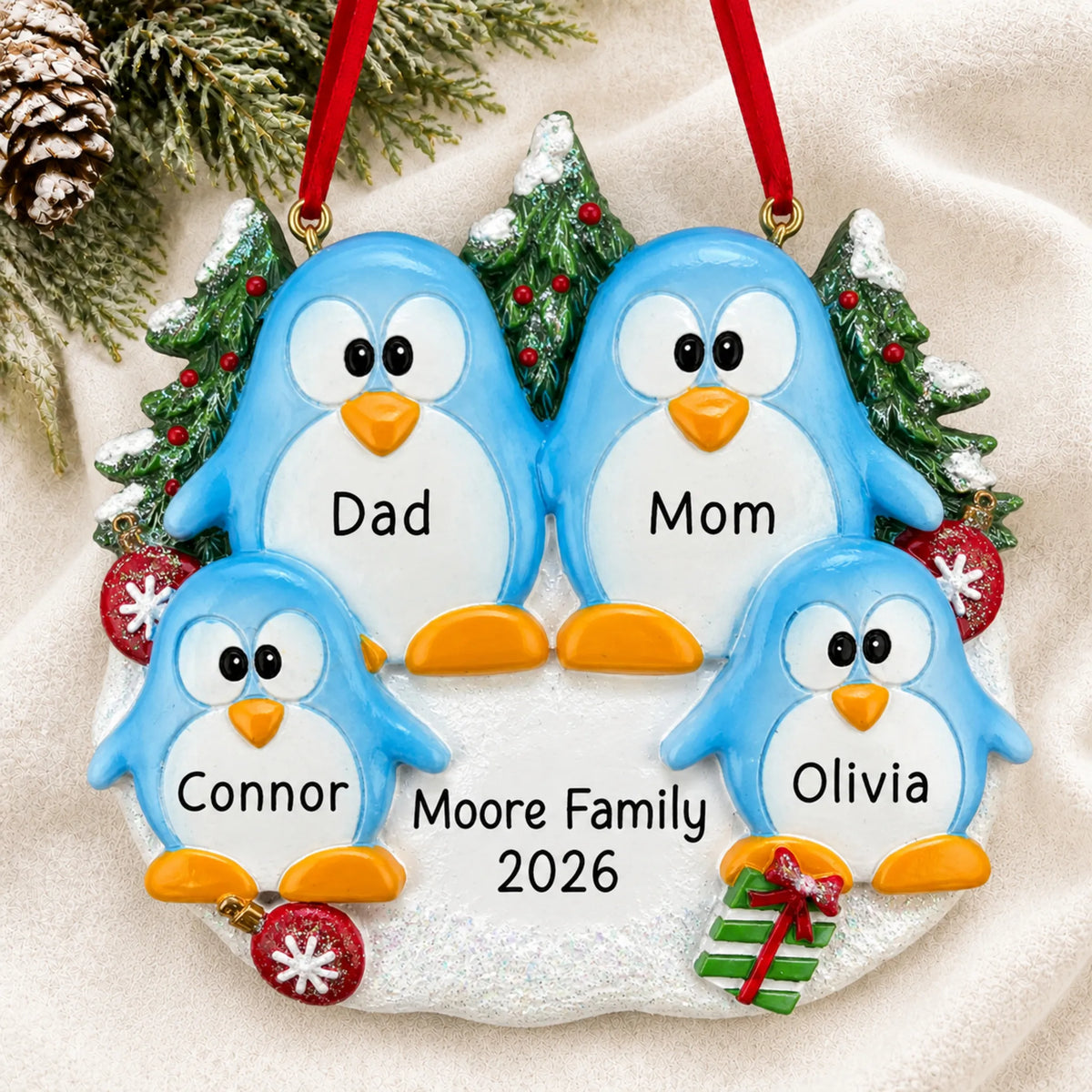 Personalized penguin family of 4 christmas ornament laid on a soft white knit blanket