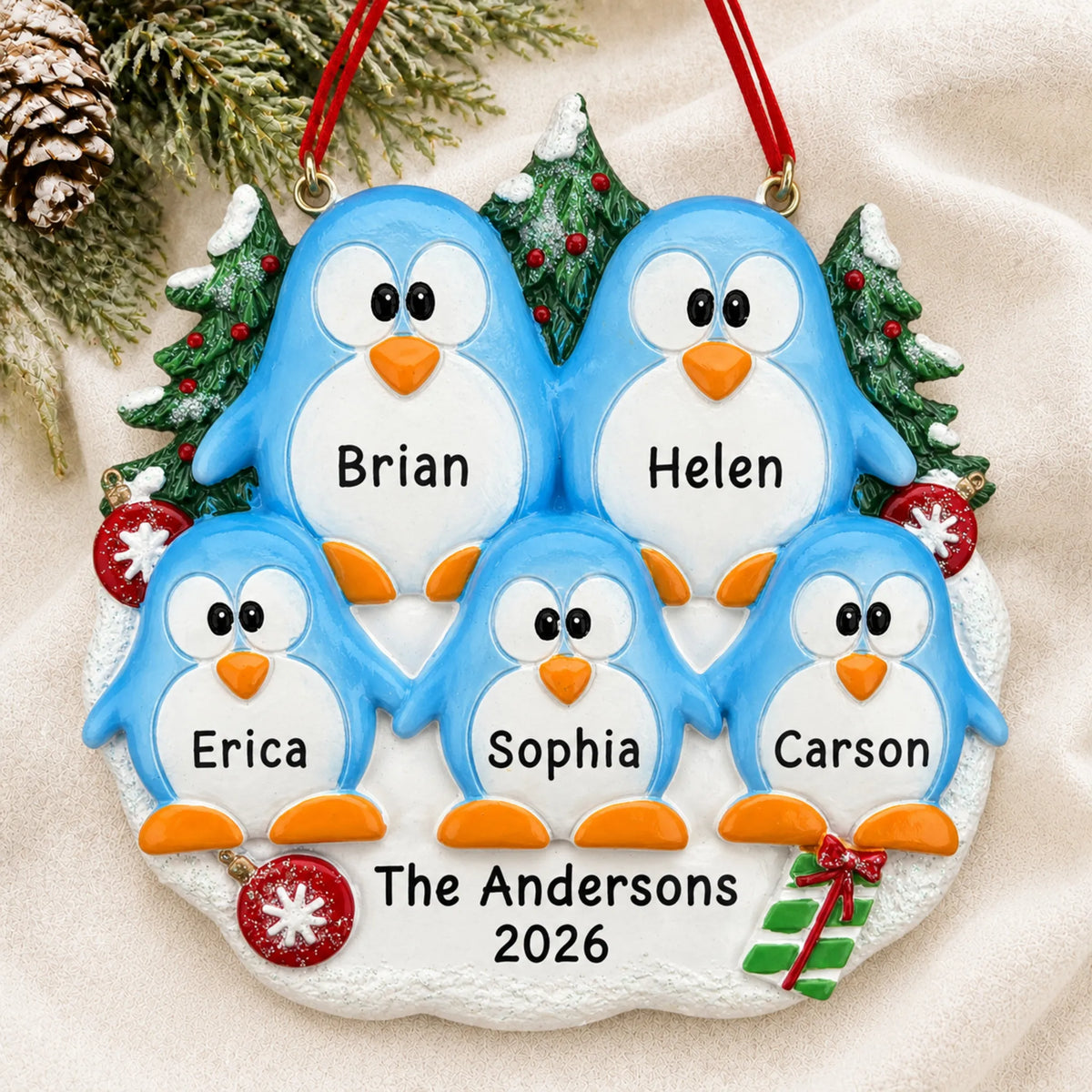 Personalized penguin family of 5 christmas ornament laid on a soft white knit blanket