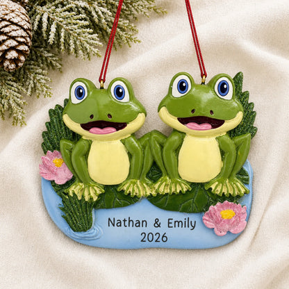 Personalized frog pond couple christmas ornament laid on a soft white knit blanket