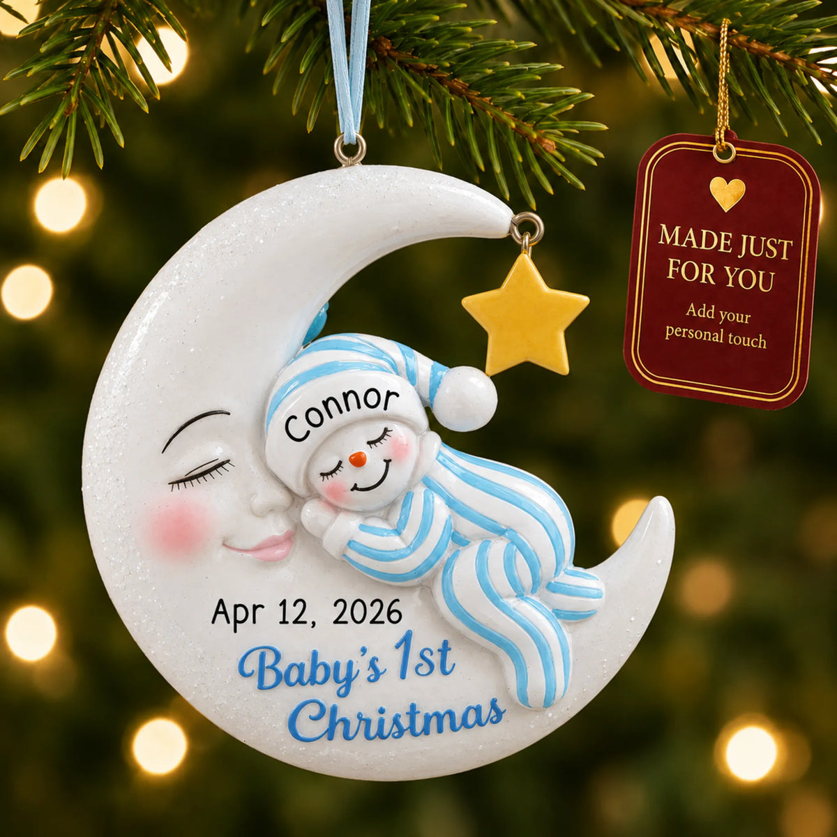 Blue snowman baby's 1st christmas ornament hanging on a lit Christmas tree with a Made Just For You gift tag