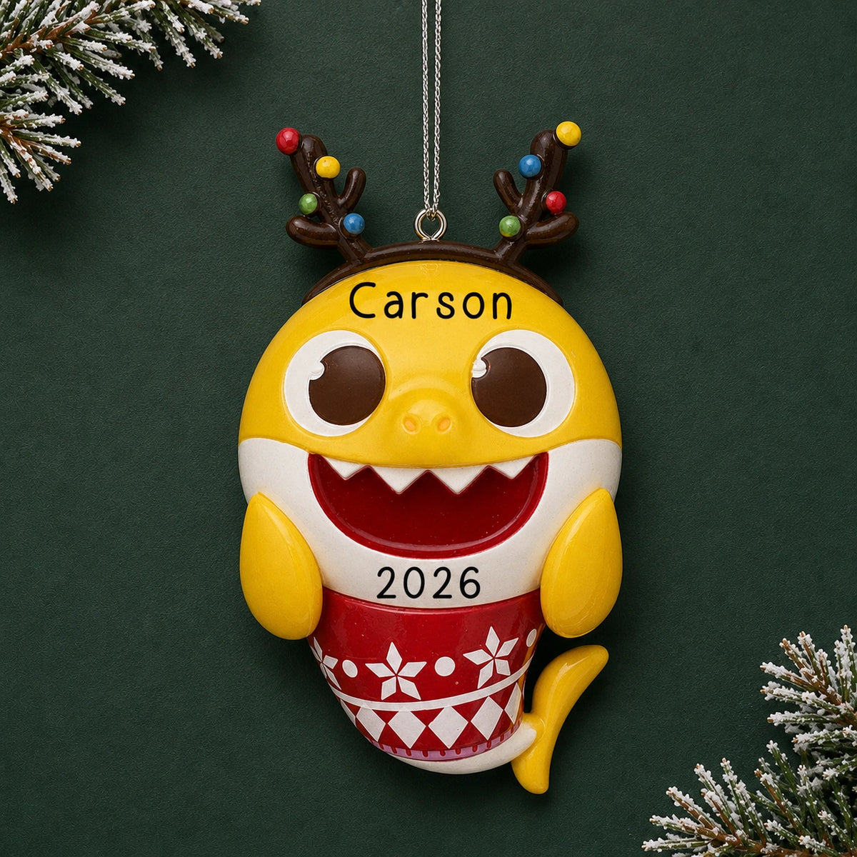 Personalized Baby Shark Christmas ornament reading Carson 2026, shown on a dark green background with pine
