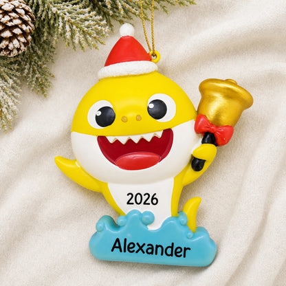 Personalized Baby Shark Santa Hat christmas ornament laid on a soft white knit blanket