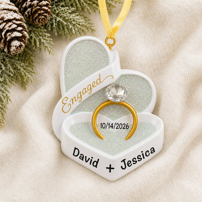 Personalized engagement ring box Christmas ornament on a cream knit blanket beside pine and pinecones
