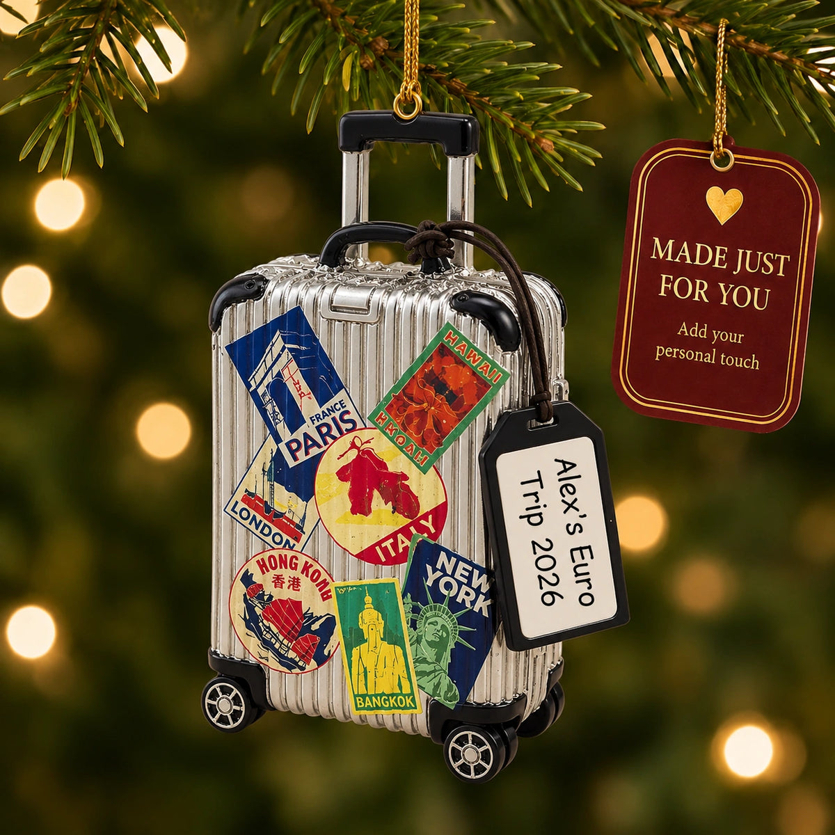 Personalized travel suitcase Christmas ornament hanging on a lit Christmas tree beside a Made Just For You gift tag